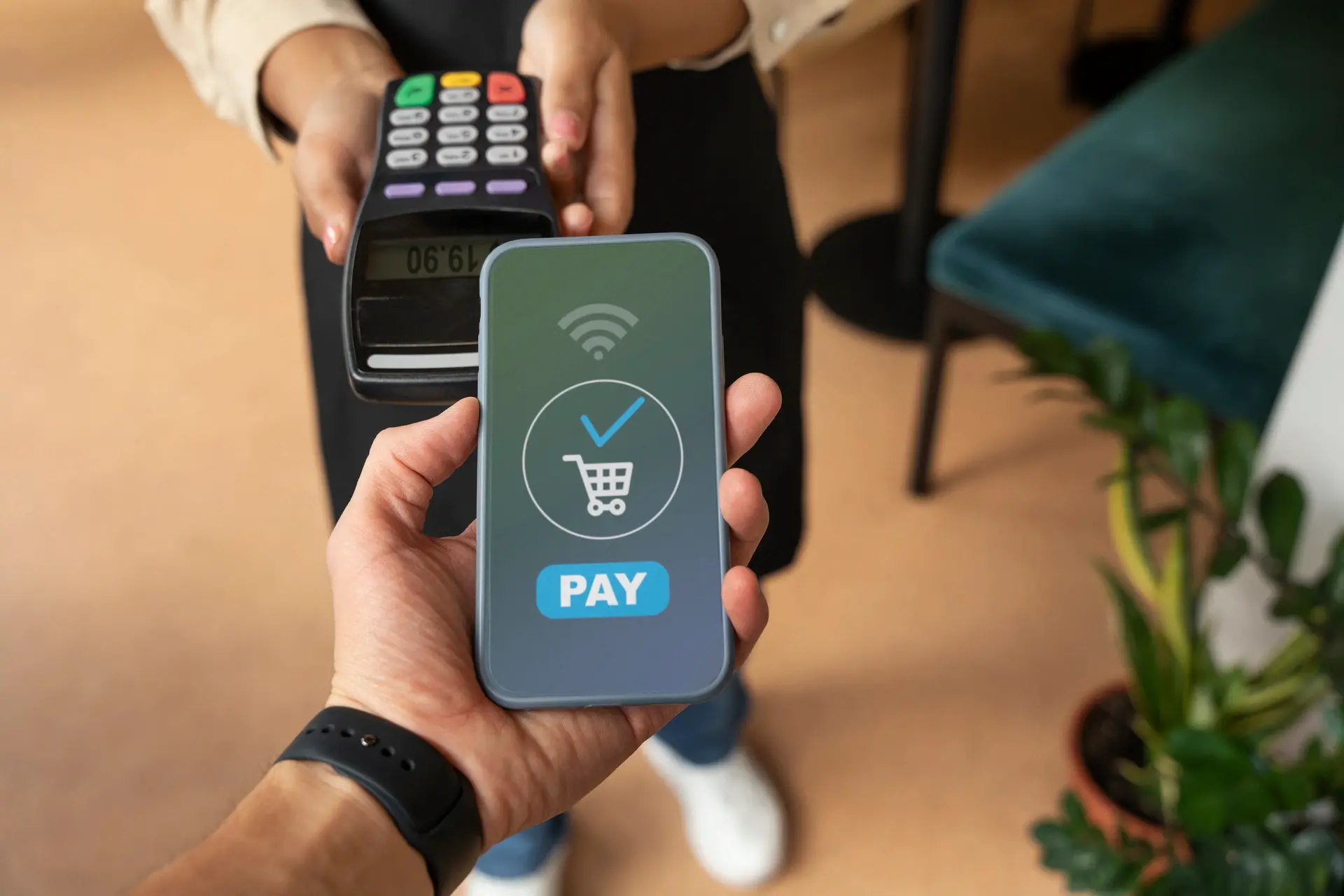 Two people engaged in a contactless payment. One holds a smartphone displaying a payment app, while the other holds a payment terminal showing a transaction amount.