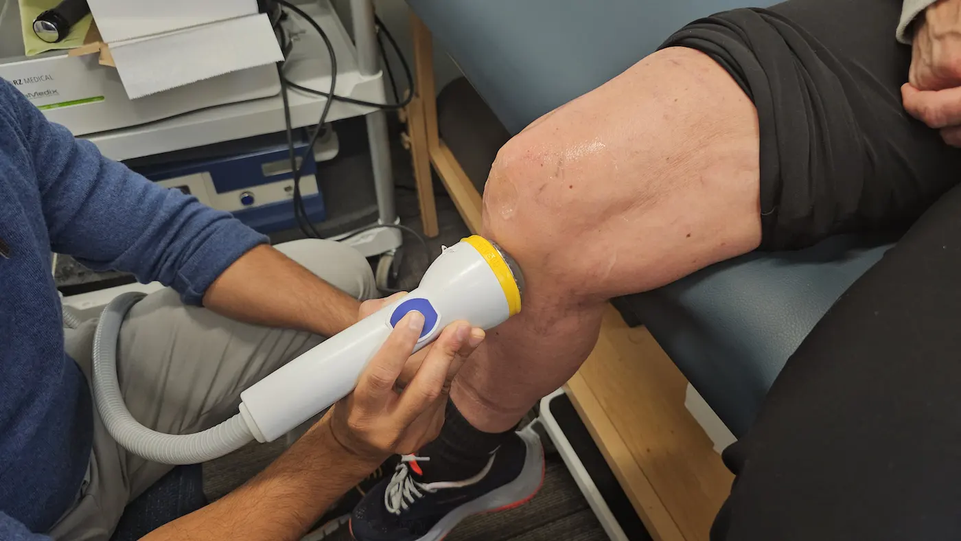 Close-up of a medical device being applied to a patient's knee, which has gel on it.